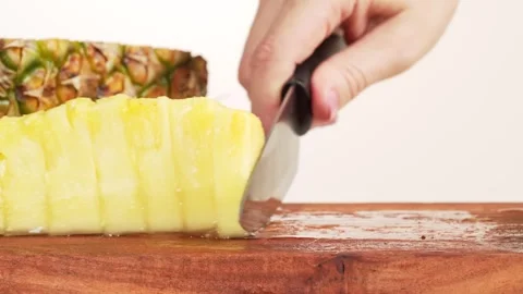 Macro view of a female hand sliding pineapple pieces aside with a knife. Gr.. Stock Footage 314431479
