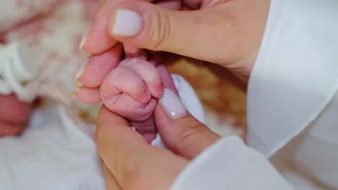 A macro view follows a mother caring for baby hands, spreading cream across tiny Stock Footage 334120749