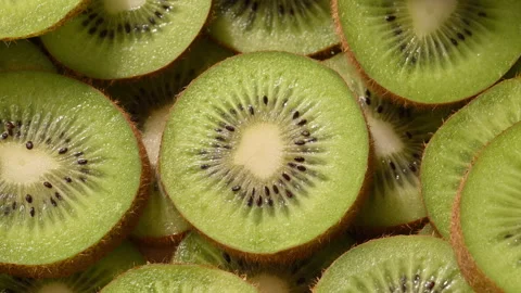 Macro view of fresh kiwi slices with warm summer sunlight moving across the Видео 330477396