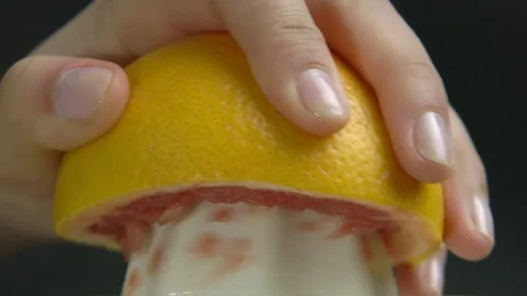 Macro View Hand with Squeezer Squeezing Grapefruit Juice, Grey Background Stock Footage 76521518
