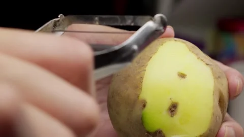Macro view of hands peeling raw potato for meal Stock Footage 334943927