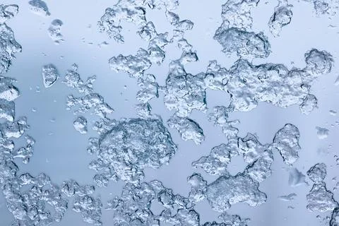 Macro view of irregular clear ice crystals on pale blue background for wint.. 库存照片