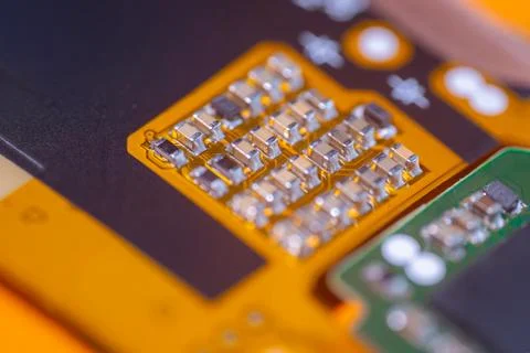 Macro view of metallic electronic components on orange circuit board with b.. Stock Photos