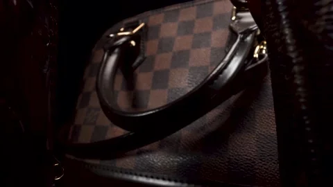 Macro view moving backward past expensive luxury leather bags in dark Stock Footage 138051139