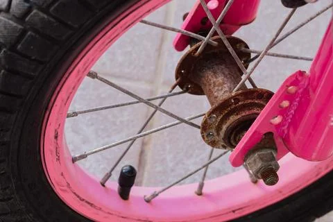 Macro view of old rusty hub and spokes on pink front wheel of children bicy.. Stock Photos