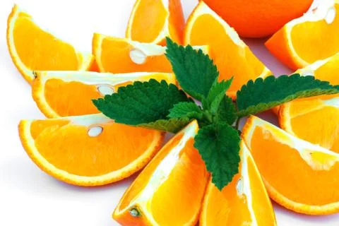 Macro view of orange with sections and green leaf of mint on white background Stock Photos
