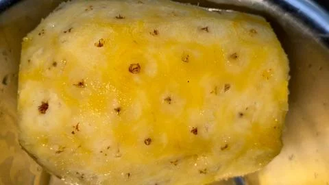 Macro view of a peeled pineapple in a stainless bowl shows its yellow flesh a Fotos Stock