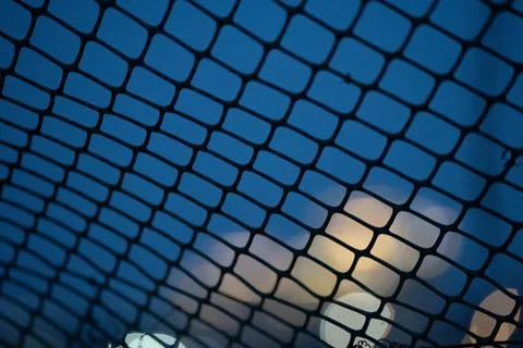 Macro view of a plastic mesh fence creating a geometric pattern against a blue Foto stock