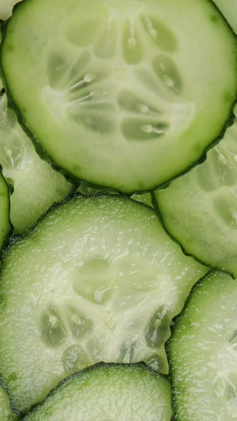 Macro view of rotating cucumber slices revealing juicy flesh and vibrant green Stock Footage 314363611