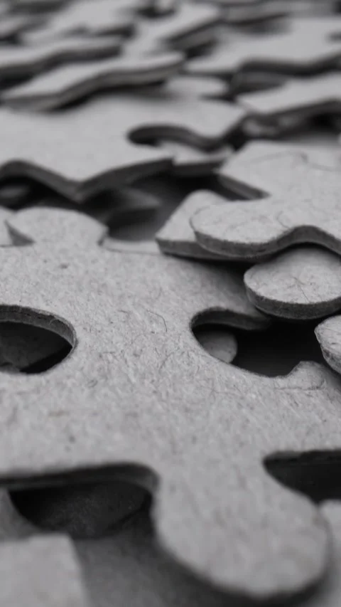 Macro view of scattered connected cardboard puzzle pieces in monochrome tones Stock Footage 341530588