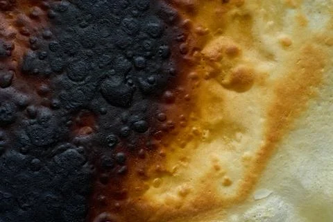 Macro view of a scorched, rough surface, revealing a gradient of black charring Stockfoto's