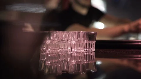 Macro View of Shot Glasses in Night Club Bar against Bartender Stock Footage