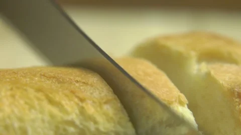 Macro View of Slicing Freshly Baked White Bread with Knife Stock Footage 76522020