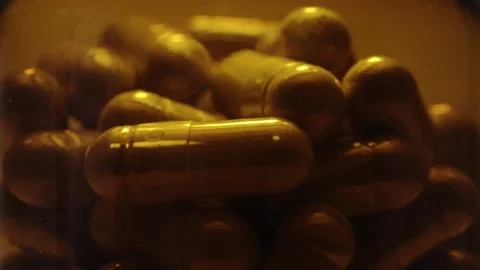 Macro view of supplement capsules slowly rotate inside amber pill bottle under Stock Footage 323906327