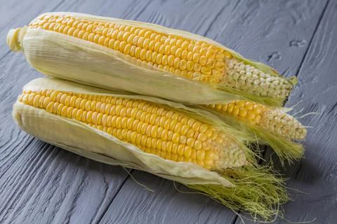 Macro view of three corn cobs pile on the wooden table. Nice macro background of Stock-Fotos