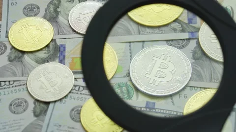 Macro view through a magnifying glass on a bitcoin coins on a table with dollars Stock Footage 201468296