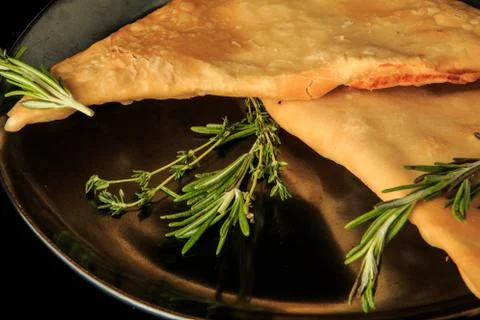 Macro view of two fried caucasian chebureki with green rosemary Foto stock