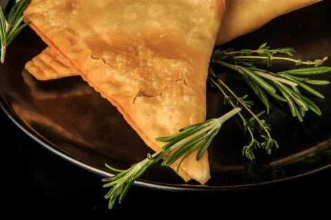 Macro view of two fried caucasian chebureki with green rosemary Foto stock