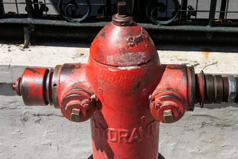 Macro view of upper part of red vintage metal fire hydrant on city pavement Stock Photos