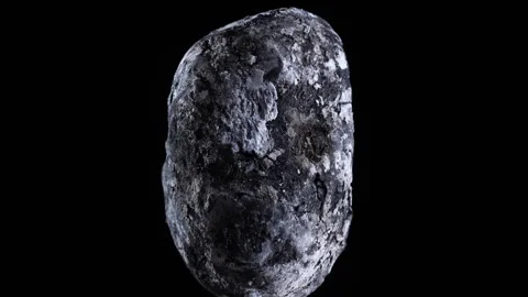 Macro view of a whole potato baked in coals on black background, rotates Video stock 345815536