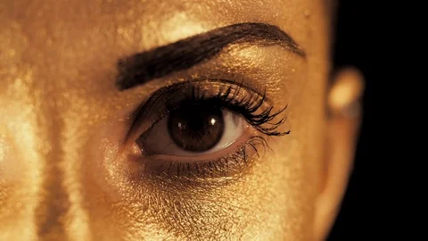 Macro view of woman's face with beautiful golden body art looking to camera, eye Stock Footage 88305799