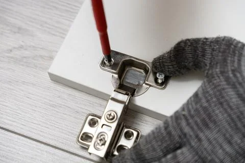Macro view of worker hand in protective glove tightening small screw on metal Фото