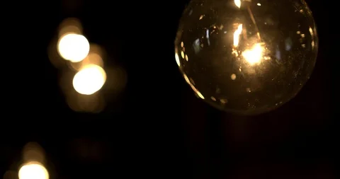 Macro of vintage lightbulb with string of lights in the background Stock Footage 98365451