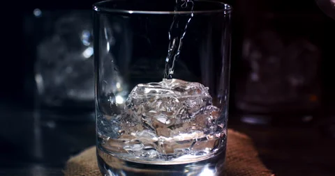 Macro of vodka poured by bartender in transparent glass with fresh cool ice Stock Footage 269934274