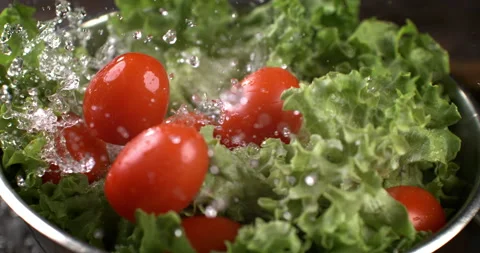 Macro of water drops fall on fresh tomatoes and green salad while being washed Stock Footage 268989036