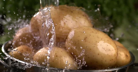 Macro of water drops fall on raw organic potatoes while being washed in colander Stock Footage 268990040