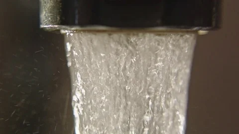 Macro of water pouring out of tap slow motion Stock Footage