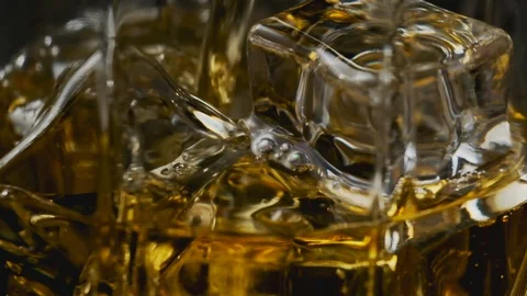 Macro of whiskey pouring in glass with ice cubes in slow motion. Alcohol pouring Video stock 123766778