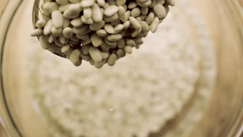Macro white beans dropping from skimmer into water 10bit Stock Footage 333152557