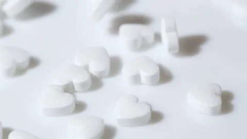Macro white heart shape drugs, closeup medical pills falling, medicine concept Stockbeeldmateriaal 233399014