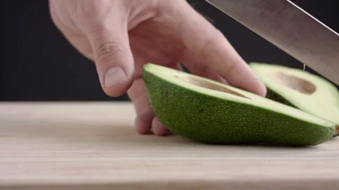 Macro wide close up of knife slicing and chopping a green avocado Stock Footage 273511488