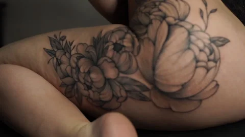 Macro young woman shows large peony tattoo on left thigh Stock Footage