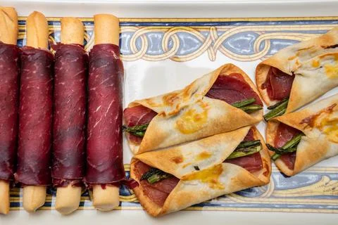Macro zenithal view of salted ham canaps with wild asparagus wrapped in a bak Stock Photos