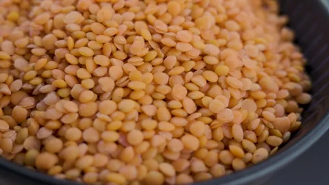 Macro zoom in on dry orange lentils in black bowl low key 4k Видео 340439435