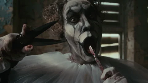 Mad Clown Twisting Curls on His Head with Knife and Then Licking Knife Stock Footage 250940403