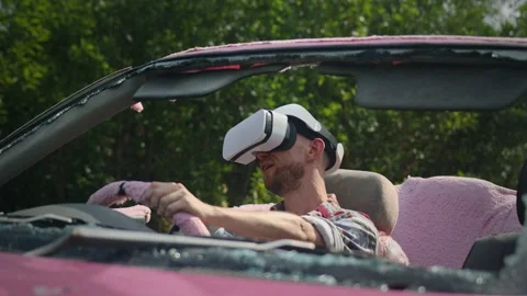 Mad man wearing vr headset drives pink shabby car outdoors Stock Footage 237042788