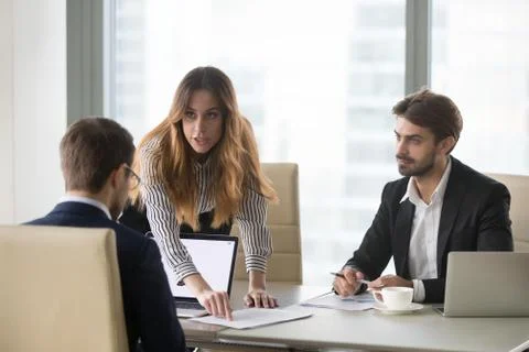 Mad woman showing document mistake to male partner during meetin Stock Photos