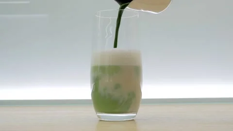Made matcha latte. Pouring matcha tea into the frothed oat milk. Stock Footage 141466434