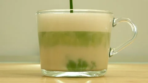 Made matcha latte. Pouring matcha tea into the frothed oat milk. Stock Footage 146861871