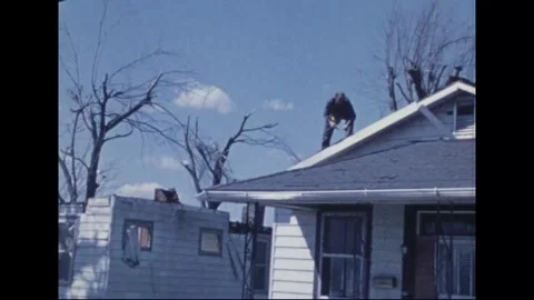 MADISON - 1974: Tornado Aftermath — Rooftop worker handles material at eaves Stock Footage 342230218
