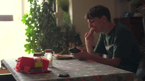 Madrid, Spain,06122025, Young man using smartphone while having breakfast Stock Footage 311567402