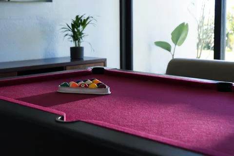 Magenta felt pool table holding metal triangle rack with colorful balls near Stock Photos