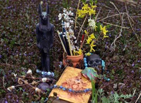 Magic book of spells with Anubis god statue and flowers on ritual altar in th Stock Photos