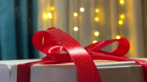 Magic dust falling on white gift box with red bow, satin ribbon Stock Footage 298702921