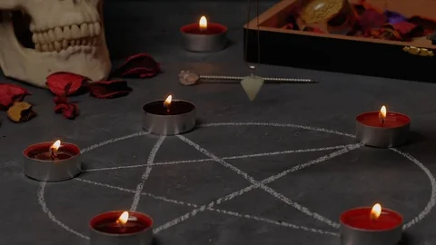 Magic pendulum rotate above the pentagram on background candles and skulls. Stock Footage 124620879