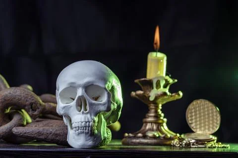 A magic skull on a wooden table, a burning candle in chains and a clock that has Фото